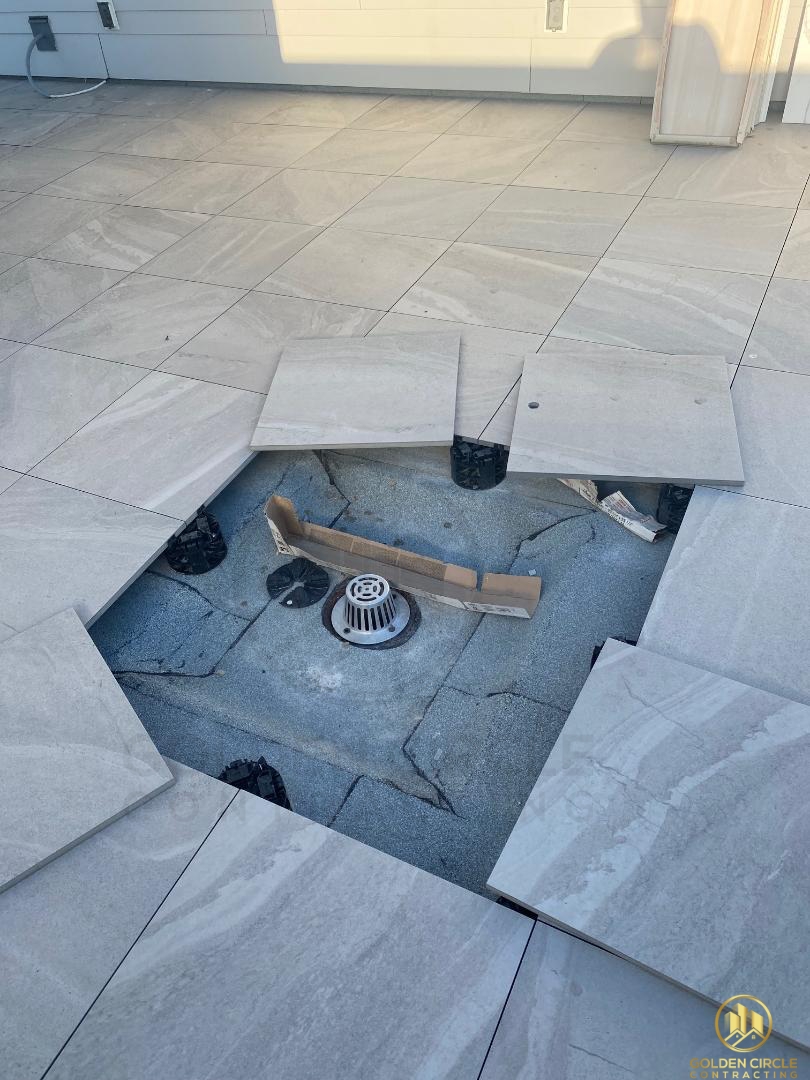 Porcelain paver installed on a pedestal support next to a rooftop drain