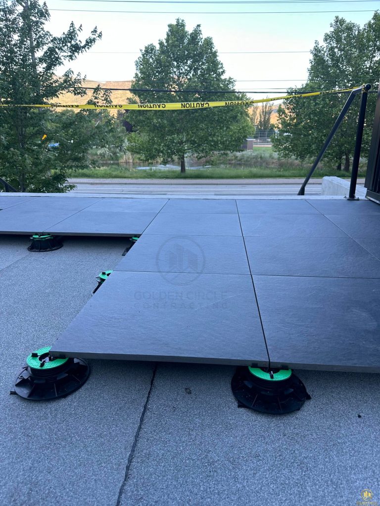 Installer setting a porcelain paver onto an adjustable pedestal support during a Vancouver rooftop installation