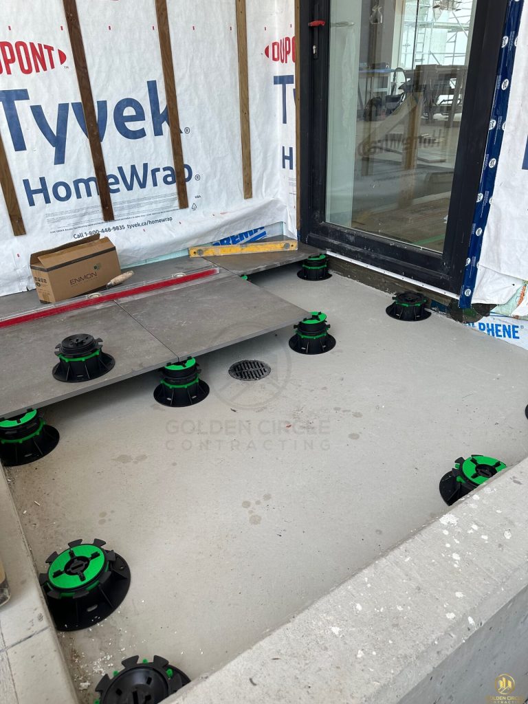 Adjustable screw-jack pedestal supports set out before paver installation on a rooftop deck